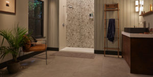 Jacuzzi walk-in shower with tile patterned wall. Installed in beige bathroom with vertically striped walls, wood cabinets, and dark crown molding